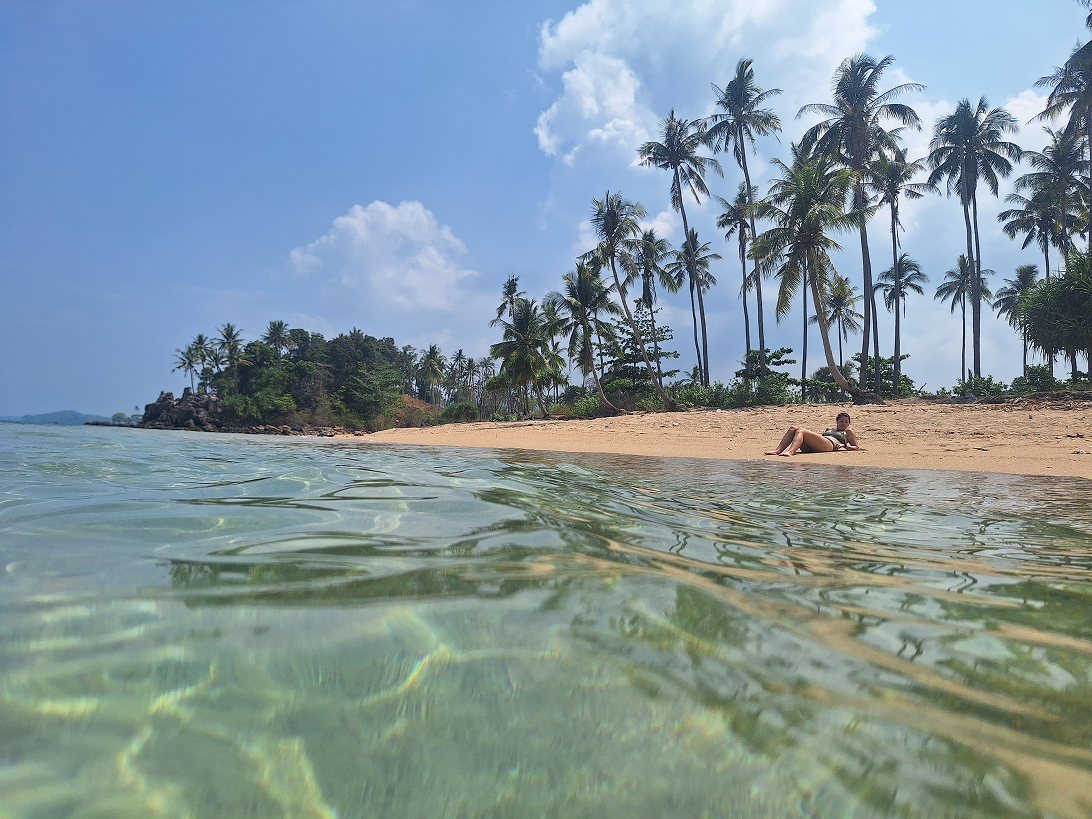 Emily lying on a beach in Koh Lanta Thailand with clear turquoise water in 2025